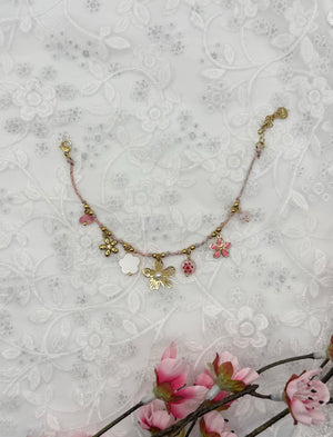 Bracelet Camelia, doré, en acier inoxydable, orné d’une petite perle rose, d’une rose dorée, d’un médaillon floral, d’une fleur nacrée et d’un trèfle scintillant