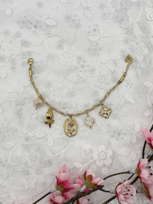 Bracelet Opalys, doré, en acier inoxydable, orné de fleurs dorées, d’un trèfle blanc, de charms floraux roses et d’une perle