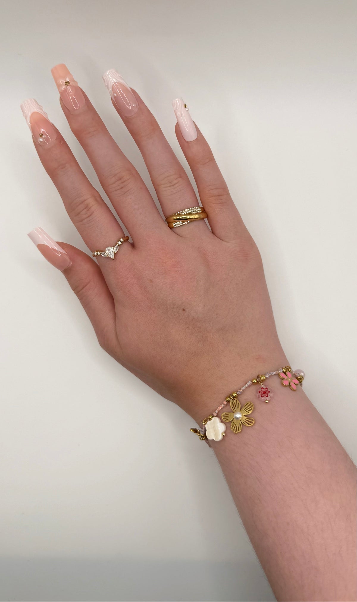 Bracelet Camelia, doré, en acier inoxydable, orné d’une petite perle rose, d’une rose dorée, d’un médaillon floral, d’une fleur nacrée et d’un trèfle scintillant